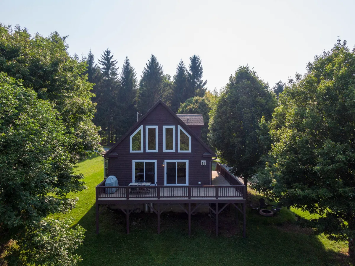 This image captures the exterior of the house featuring large windows, a spacious deck, and a lush green lawn. The inviting outdoor environment hints at ample space for pets to run and play, and the deck provides a relaxing spot for guests and their furry friends alike.