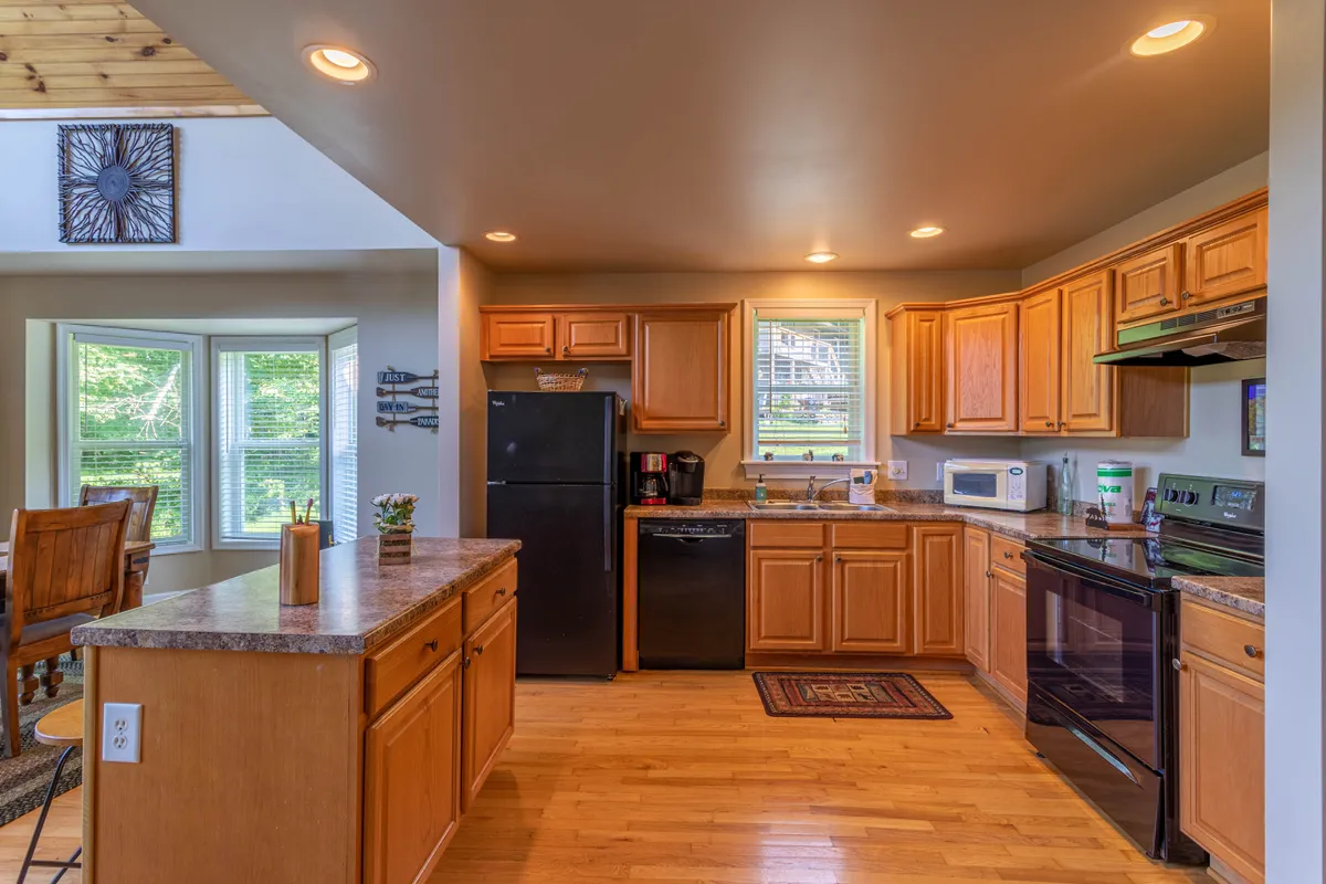 A bright kitchen area with a central island perfect for meal prep or casual dining, window seating for enjoying a peaceful moment with coffee, and modern appliances including both Keurig and drip coffee makers. The open design keeps the cook connected with the rest of the group, and natural light floods the space, enhancing its welcoming feel.